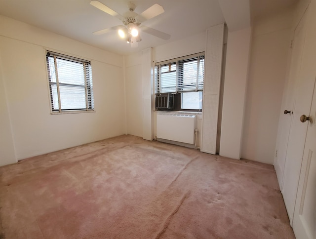 carpeted spare room with ceiling fan, radiator heating unit, and a healthy amount of sunlight