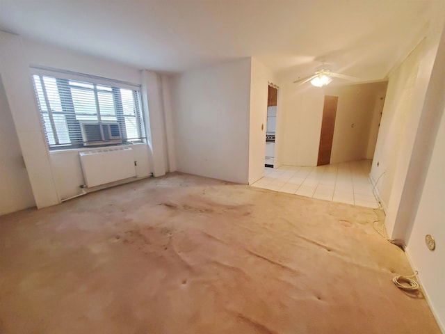 tiled spare room featuring ceiling fan and radiator heating unit