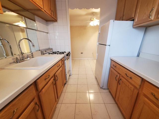 kitchen with ceiling fan, sink, gas range oven, backsplash, and white fridge