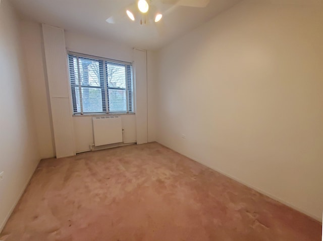 empty room featuring carpet flooring, radiator heating unit, and ceiling fan