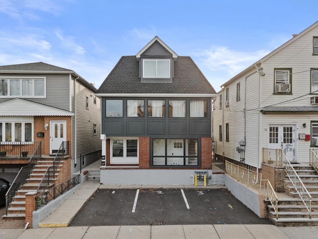 view of front of home featuring a shingled roof, cooling unit, and brick siding