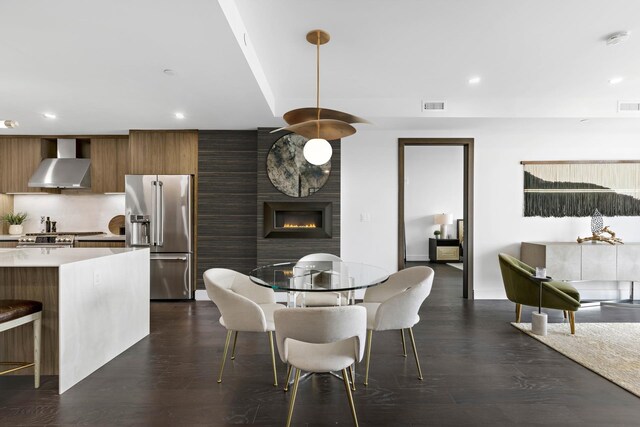 dining room with dark hardwood / wood-style floors and a large fireplace