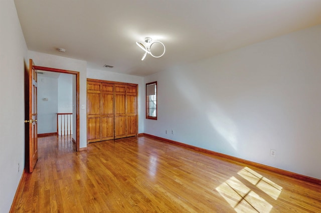 unfurnished bedroom featuring light wood-style flooring, baseboards, and a closet
