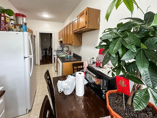 36 Duncan Ave Unit D2, Jersey City, NJ 07304 - kitchen featuring white appliances, brown cabinetry, a textured ceiling, light tile patterned floors, and dark countertops