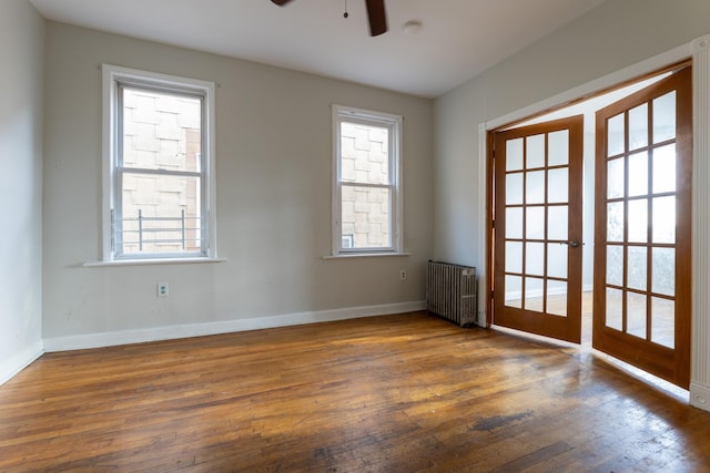 empty room featuring ceiling fan, dark wood-type flooring, radiator, and french doors