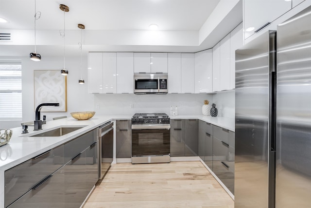 kitchen with white cabinets, sink, stainless steel appliances, and hanging light fixtures