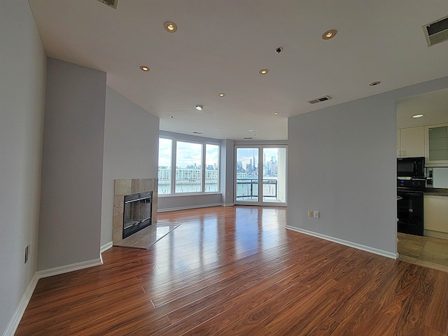 unfurnished living room featuring a tile fireplace and hardwood / wood-style flooring