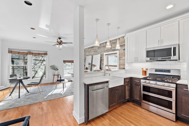 kitchen featuring white cabinetry, sink, stainless steel appliances, and hanging light fixtures