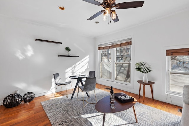 living area featuring hardwood / wood-style flooring, crown molding, and ceiling fan