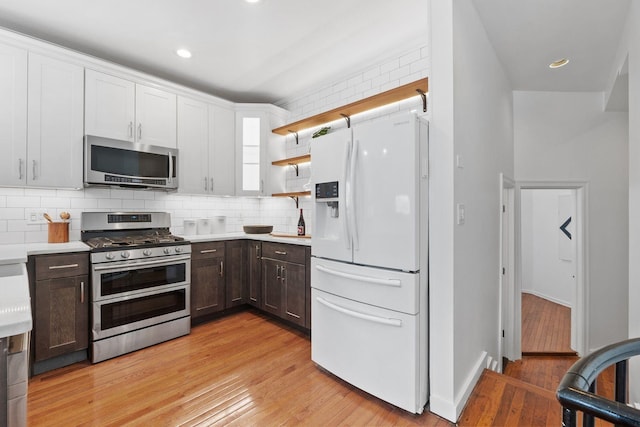 kitchen with stainless steel appliances, tasteful backsplash, dark brown cabinets, and light hardwood / wood-style floors