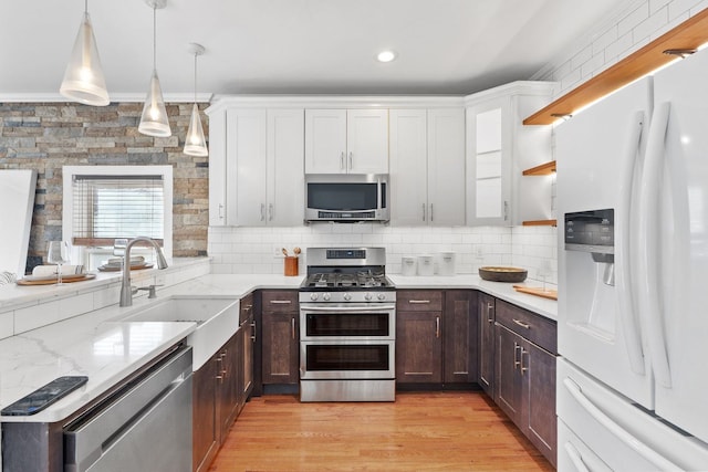 kitchen featuring pendant lighting, stainless steel appliances, sink, and white cabinets