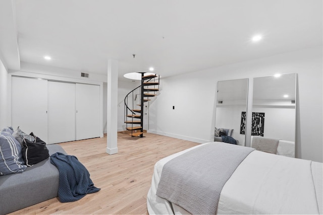 bedroom with light hardwood / wood-style floors and a closet