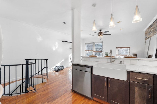 kitchen featuring decorative light fixtures, sink, stainless steel dishwasher, dark brown cabinetry, and light hardwood / wood-style flooring