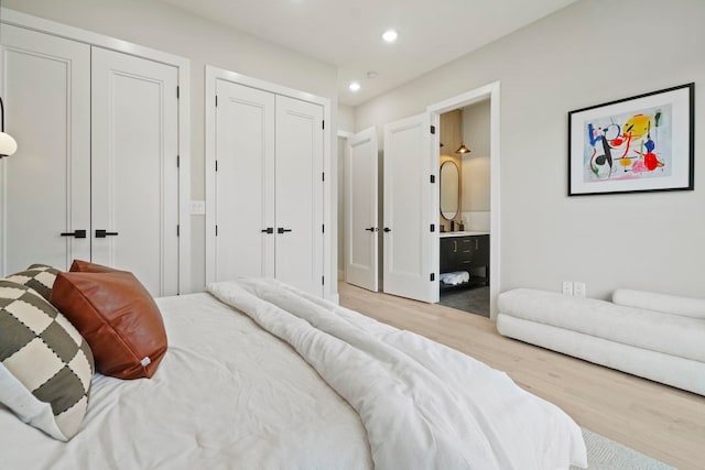 bedroom featuring light hardwood / wood-style flooring, connected bathroom, and two closets