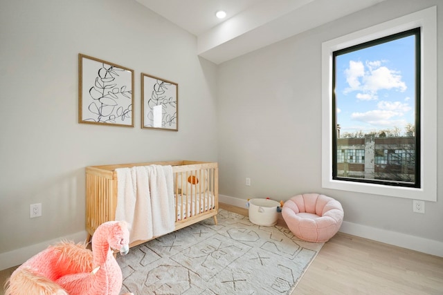 bedroom featuring light hardwood / wood-style floors and a crib