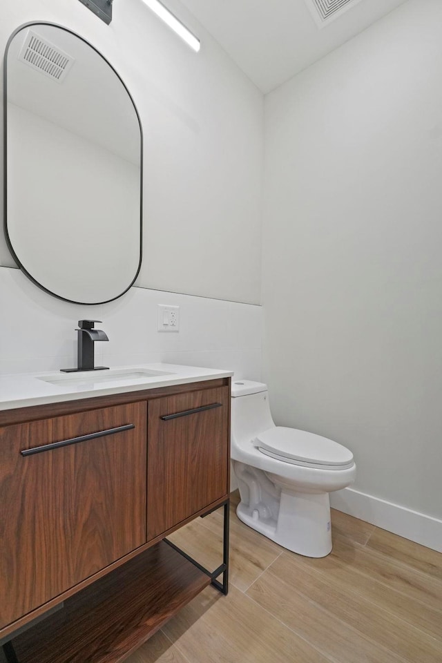 bathroom featuring wood-type flooring, toilet, and vanity