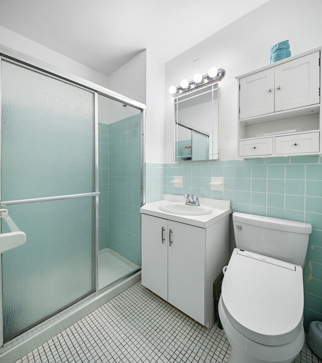 full bathroom featuring tile walls, toilet, a shower stall, vanity, and tile patterned floors