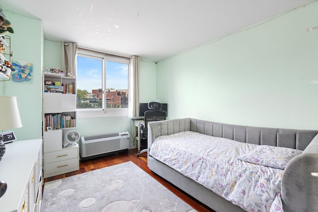 bedroom featuring wood finished floors and a wall unit AC