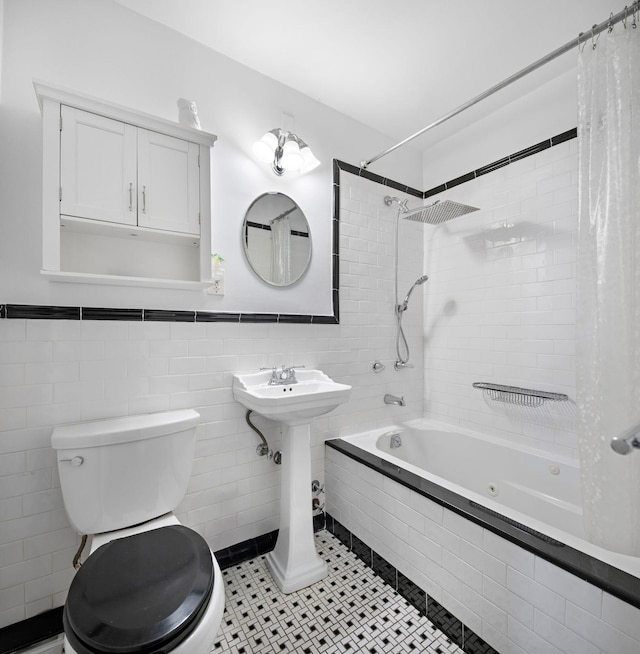 full bath with tiled shower / bath combo, toilet, tile patterned floors, wainscoting, and tile walls