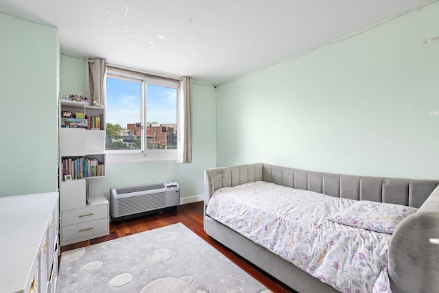 bedroom featuring wood finished floors and an AC wall unit