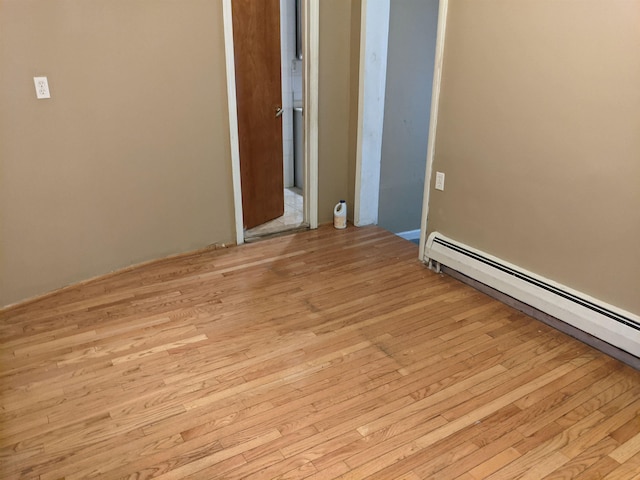 unfurnished room featuring a baseboard heating unit and light wood-type flooring