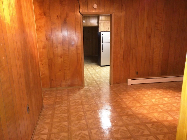 unfurnished room featuring a baseboard radiator, wooden walls, and light parquet floors