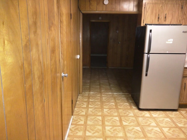 kitchen with light parquet flooring, wooden walls, and refrigerator