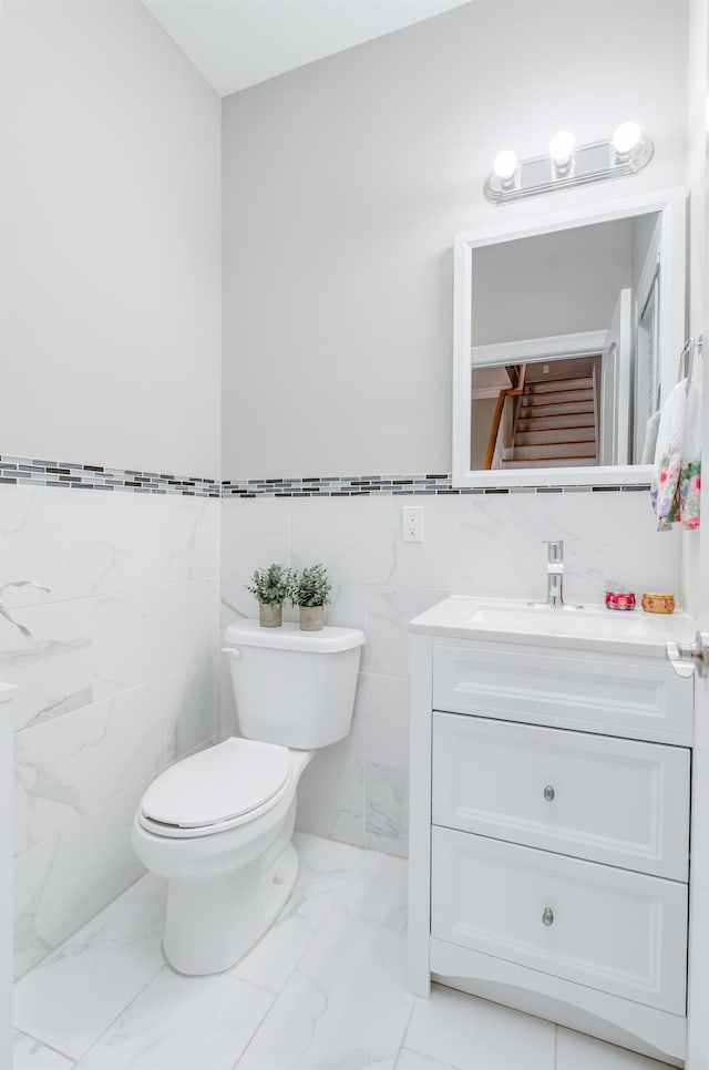 347 Forest St, Kearny, NJ 07032 - half bath with marble finish flooring, vanity, toilet, tile walls, and a wainscoted wall