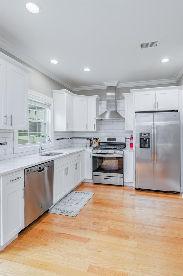 347 Forest St, Kearny, NJ 07032 - kitchen featuring appliances with stainless steel finishes, wall chimney range hood, a sink, ornamental molding, and white cabinets