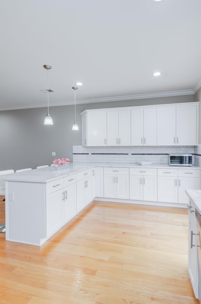 347 Forest St, Kearny, NJ 07032 - kitchen with crown molding, light countertops, white cabinetry, a peninsula, and hanging light fixtures
