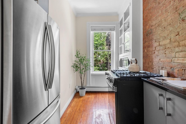 112 Wayne St Unit 2-A, Jersey City, NJ 07302 - kitchen featuring stainless steel appliances, a baseboard radiator, light wood-style floors, crown molding, and dark countertops