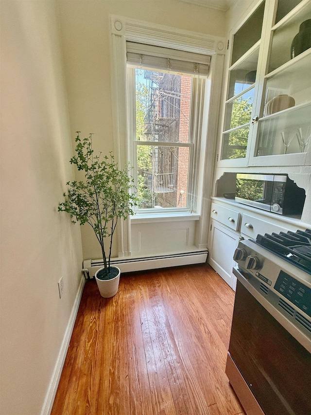 112 Wayne St Unit 2-A, Jersey City, NJ 07302 - interior space with stainless steel gas range, wood finished floors, and a baseboard radiator