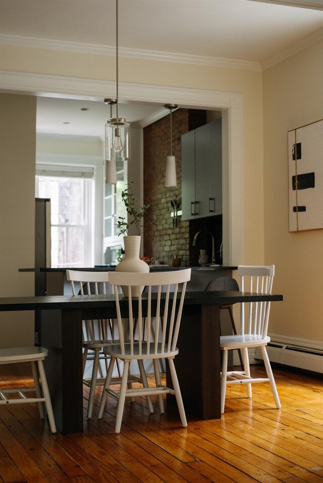 112 Wayne St Unit 2-A, Jersey City, NJ 07302 - kitchen featuring hardwood / wood-style floors, a breakfast bar, ornamental molding, hanging light fixtures, and dark countertops