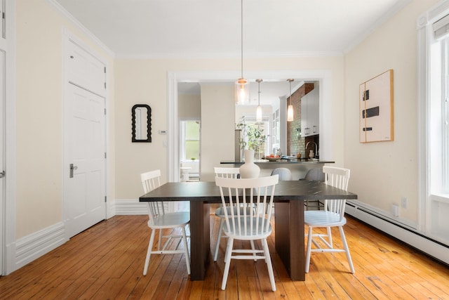 112 Wayne St Unit 2-A, Jersey City, NJ 07302 - dining space with a baseboard heating unit, light wood-type flooring, healthy amount of natural light, and ornamental molding