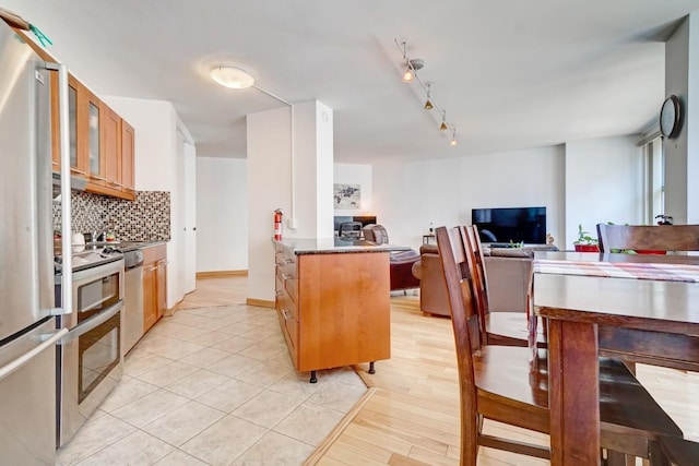 kitchen with backsplash, stainless steel appliances, and light hardwood / wood-style floors