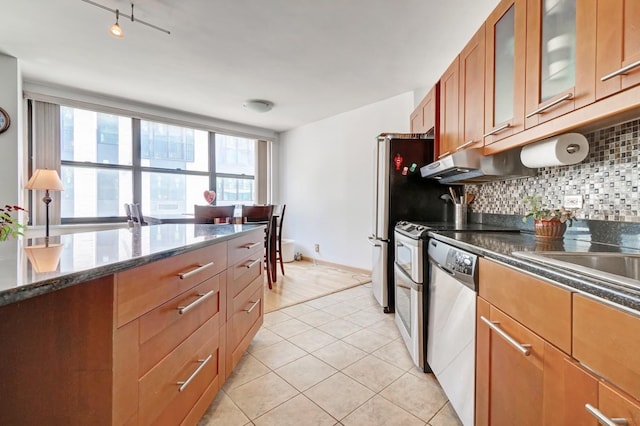 kitchen with tasteful backsplash, stainless steel dishwasher, dark stone counters, and light tile patterned floors