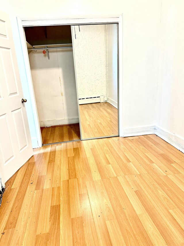 306 Columbia Ave, Jersey City, NJ 07307 - unfurnished bedroom featuring a baseboard heating unit, wood finished floors, and a closet