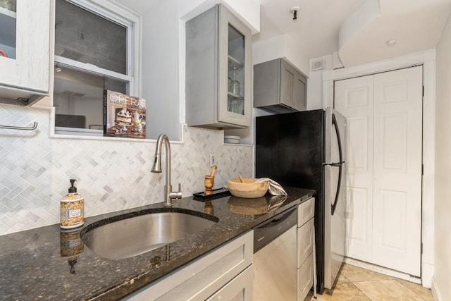 kitchen featuring stainless steel appliances, a sink, dark stone countertops, and tasteful backsplash