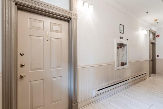 hall featuring a baseboard radiator, a wainscoted wall, and ornamental molding