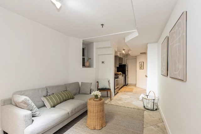 living area featuring light stone finish flooring and baseboards