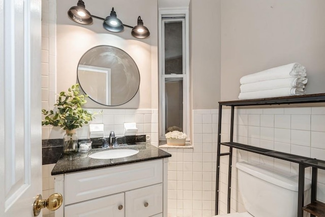 bathroom featuring tile walls, toilet, and vanity