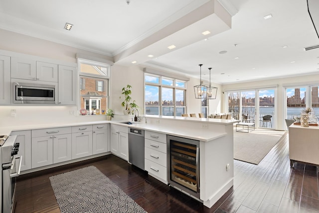 kitchen featuring crown molding, a sink, beverage cooler, stainless steel appliances, and a peninsula