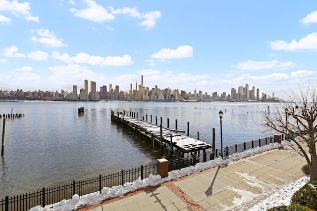 dock area with a water view, fence, and a city view