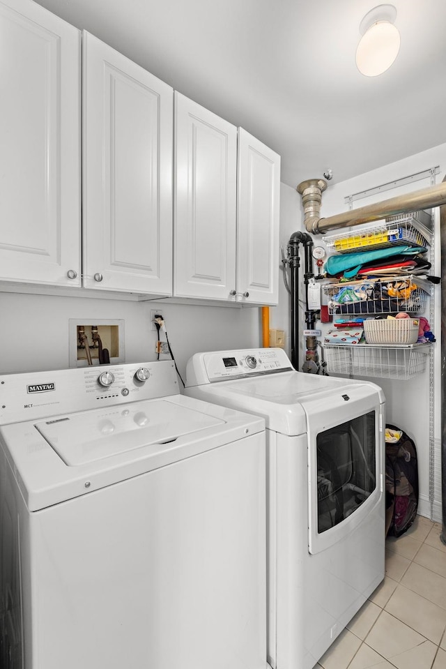 laundry area featuring cabinet space, light tile patterned floors, and washing machine and dryer