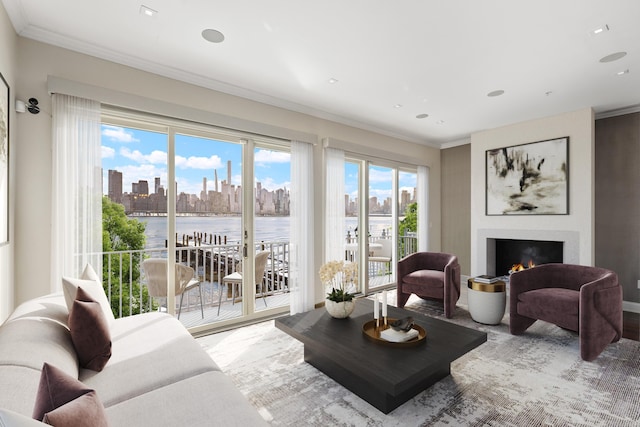 living room with a lit fireplace, a city view, a water view, ornamental molding, and recessed lighting