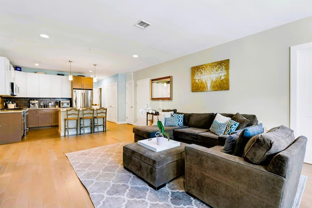 living room with recessed lighting, visible vents, and light wood-style flooring