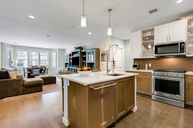 kitchen with visible vents, open floor plan, light countertops, tasteful backsplash, and appliances with stainless steel finishes