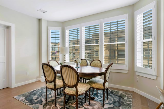 dining area with baseboards, a healthy amount of sunlight, and wood finished floors
