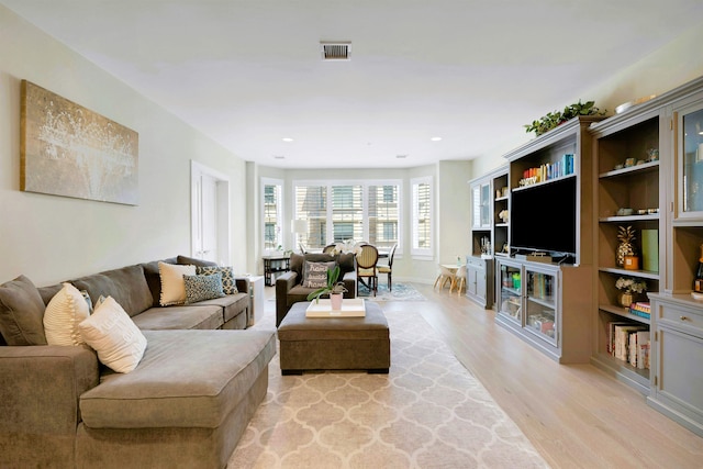 living room featuring light wood-type flooring, recessed lighting, baseboards, and visible vents