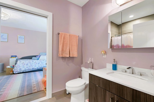 bathroom featuring curtained shower, vanity, baseboards, toilet, and ensuite bathroom